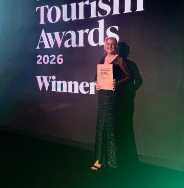 Michelle Awards A lady with blonde hair wears a black dress, she is holding an award.